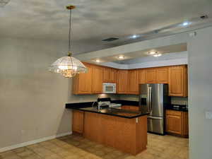 Kitchen featuring stainless steel fridge, brown cabinets, a peninsula, electric range, and recessed lighting