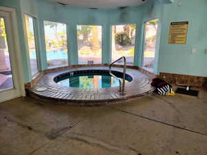 View of swimming pool with an in-ground hot tub and a sunroom
