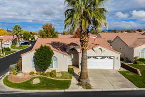 Mediterranean / spanish-style house with stucco siding, concrete driveway, a residential view, an attached garage, and a tiled roof