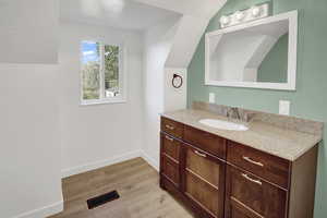 Bathroom featuring light wood finished floors, vanity, a textured ceiling, and lofted ceiling