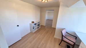 Hall featuring light wood-style flooring and a textured ceiling