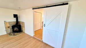 Unfurnished living room featuring a wood stove, wood finished floors, and a barn door