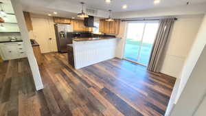 Kitchen with brown cabinets, dark stone countertops, recessed lighting, hanging light fixtures, and appliances with stainless steel finishes