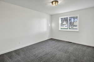 Empty room with dark colored carpet and baseboards