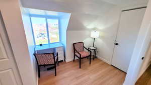 Sitting room with vaulted ceiling and light wood-style flooring