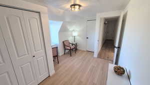 Corridor with a textured ceiling and light wood-type flooring