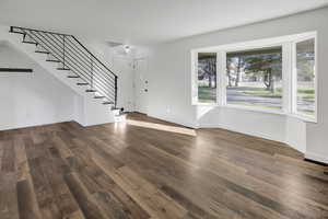Unfurnished living room with stairway and dark wood-style floors