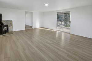 Unfurnished living room featuring a wood stove and light wood finished floors