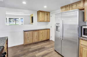 Kitchen featuring stainless steel appliances, recessed lighting, light brown cabinets, light wood finished floors, and a wainscoted wall
