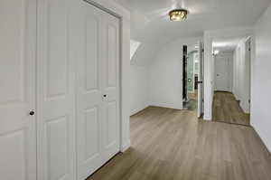 Additional living space featuring light wood finished floors and lofted ceiling