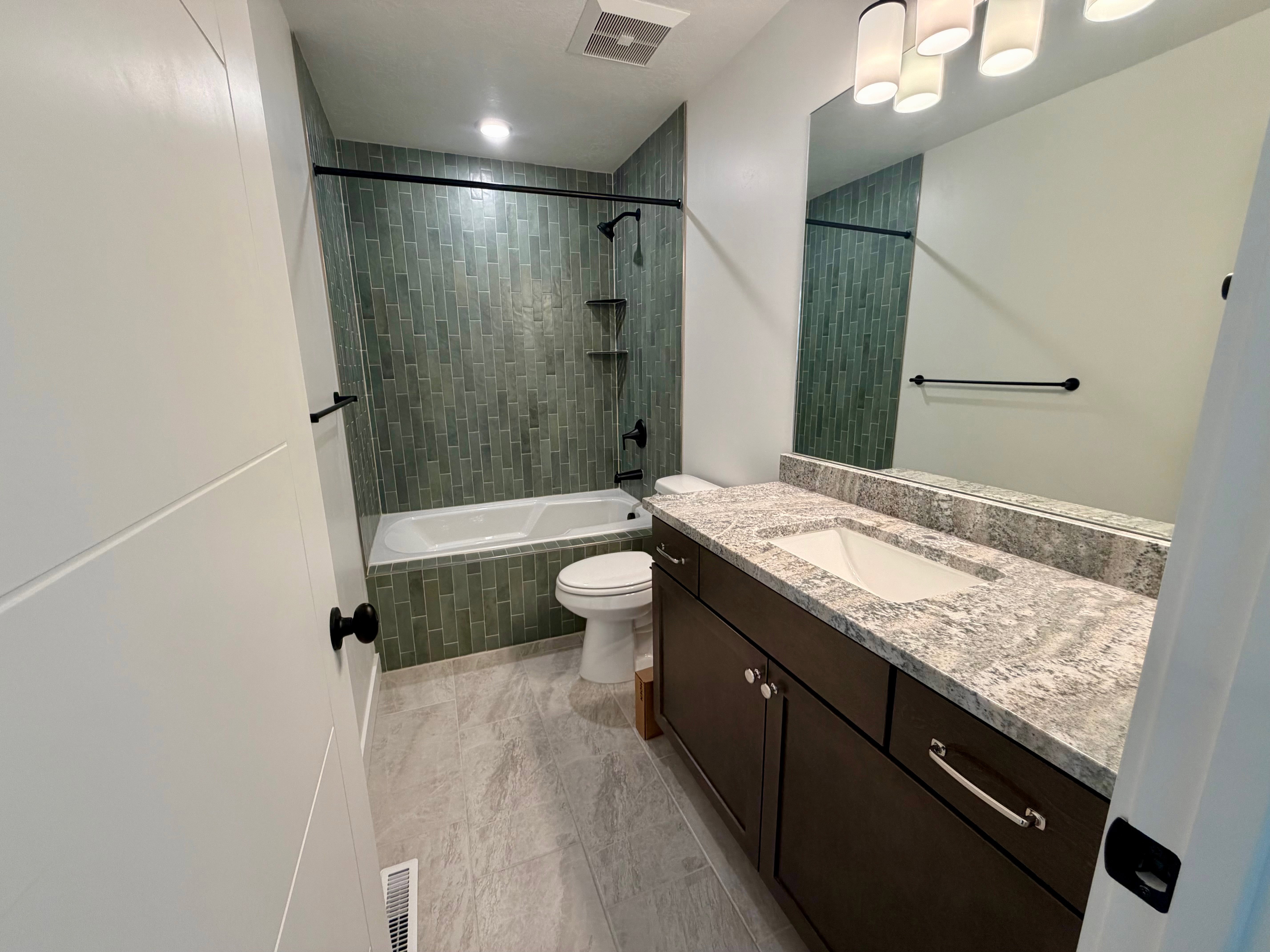 Full bathroom featuring a dark wood-finish vanity with a light-toned countertop, a rectangular undermount sink, and a large wall mirror