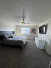 Carpeted bedroom featuring a textured ceiling and a ceiling fan