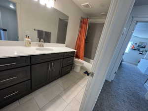 Bathroom featuring shower / bath combination with curtain, vanity, a textured ceiling, light tile patterned floors, and light carpet