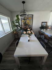 Dining room featuring a textured ceiling, dark wood-type flooring, and a chandelier