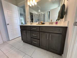 Bathroom featuring a shower stall, double vanity, and light tile patterned floors