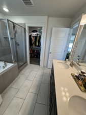Full bath with a shower stall, double vanity, a bath, a textured ceiling, and light tile patterned flooring