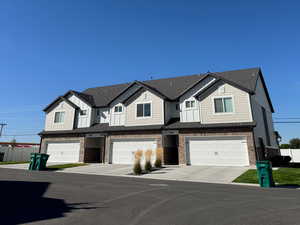 View of front of home featuring brick siding, board and batten siding, roof with shingles, and an attached garage