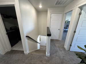 Corridor featuring an upstairs landing and light carpet