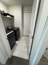 Laundry room featuring independent washer and dryer, light tile patterned floors, and light colored carpet