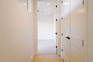 Hall with light wood-style floors and recessed lighting