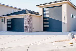 View of front of home featuring stucco siding, concrete driveway, an attached garage, and brick siding