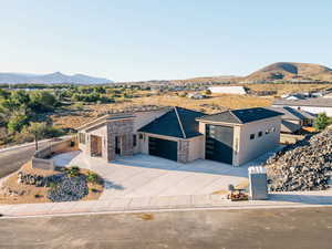 View of front of home featuring a mountain view, stucco siding, concrete driveway, an attached garage, and stone siding