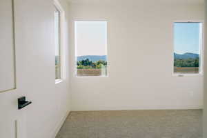 Carpeted empty room featuring healthy amount of natural light and a mountain view