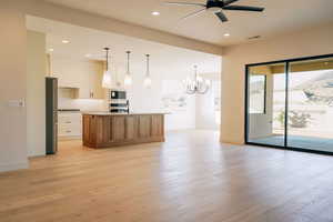 Kitchen with open floor plan, a kitchen island with sink, brown cabinetry, pendant lighting, and recessed lighting