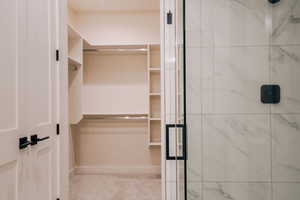 Full bath featuring a spacious closet and a marble finish shower