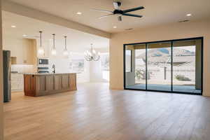 Kitchen with a kitchen island with sink, hanging light fixtures, light wood-type flooring, recessed lighting, and open floor plan