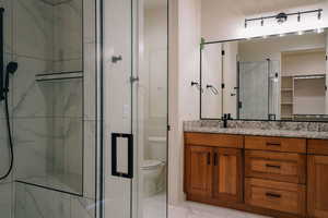 Full bath with a marble finish shower, vanity, light marble finish flooring, and a walk in closet