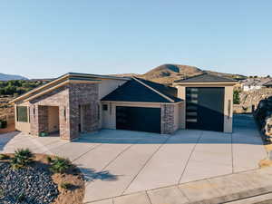 View of front of house with stucco siding, a garage, a mountain view, driveway, and brick siding