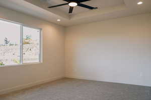 Unfurnished room featuring a raised ceiling, recessed lighting, carpet, and ceiling fan