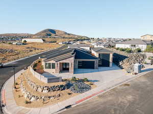 View of front of home featuring a garage, concrete driveway, brick siding, a patio, and a mountain view