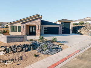 View of front of house with brick siding, an attached garage, and driveway