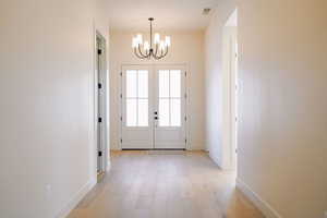 Doorway with hardwood / wood-style flooring, french doors, and a chandelier