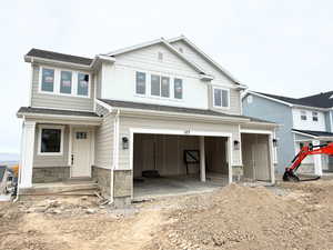 View of front of home featuring an attached garage, stone siding, board and batten siding, and a shingled roof