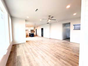 Unfurnished living room with light wood-style floors, recessed lighting, a ceiling fan, and a chandelier