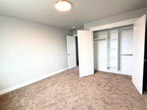 Unfurnished bedroom featuring light carpet and a closet