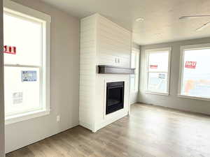 Unfurnished living room with a fireplace, light wood-style flooring, and a textured ceiling