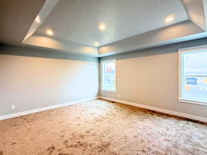 Unfurnished room with a textured ceiling, a tray ceiling, carpet floors, and recessed lighting