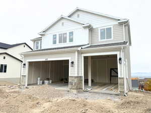 View of front of home with a garage, stone siding, and board and batten siding