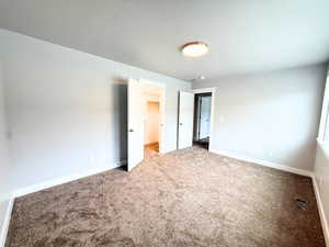 Unfurnished bedroom with a walk in closet, carpet flooring, and a textured ceiling