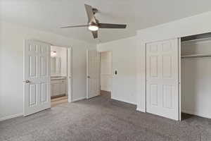 Unfurnished bedroom with a closet, carpet flooring, a ceiling fan, a textured ceiling, and ensuite bathroom