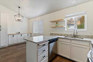 Kitchen featuring white cabinetry, a peninsula, dishwasher, light stone countertops, and pendant lighting
