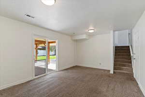 Basement featuring carpet flooring, a textured ceiling, and stairway