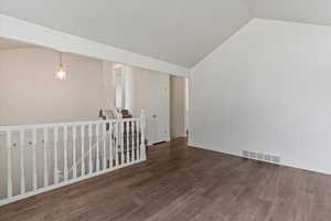 Spare room featuring dark wood-style floors and vaulted ceiling