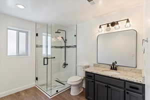 Full bathroom featuring dark wood-style flooring, vanity, and a stall shower