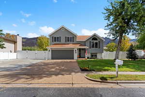 View of front of home with a gate, driveway, an attached garage, brick siding, and a mountain view