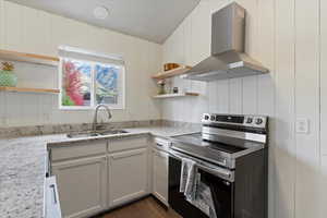 Kitchen featuring open shelves, stainless steel range with electric cooktop, wall chimney range hood, white cabinets, and light stone counters